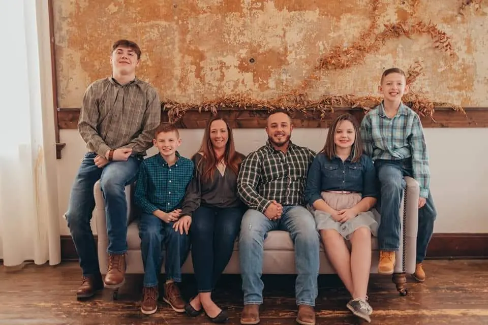 Phil Betzner seated on a couch with his wife Dawn and their four kids, everyone in plaid and denim