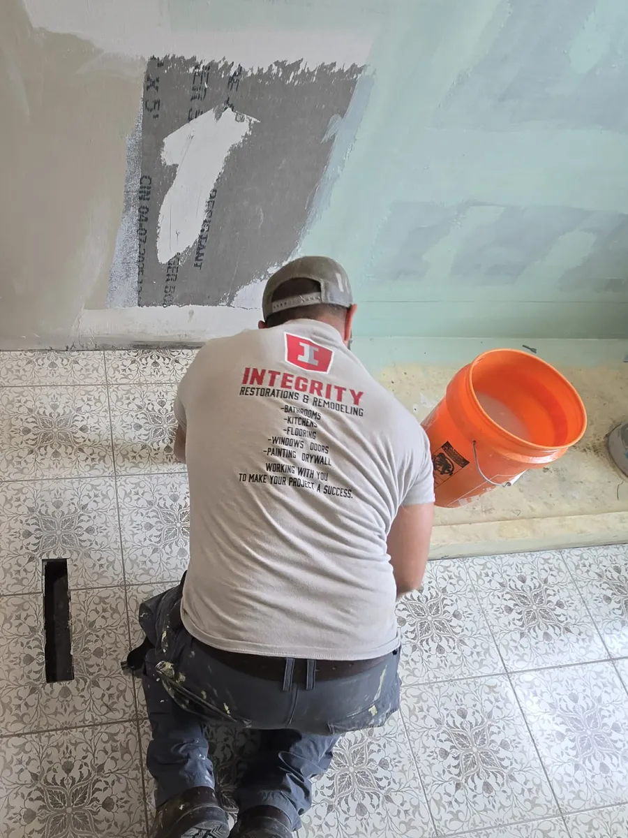 Phil kneeling in an Integrity shirt, setting patterned floor tile
