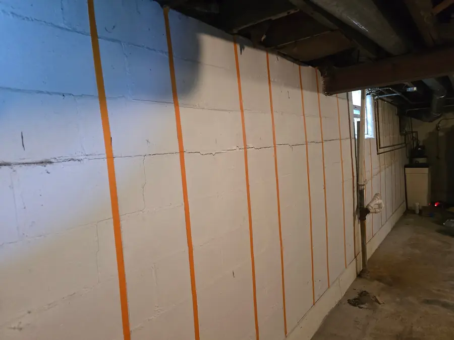 Unfinished basement before: bare block walls and exposed framing