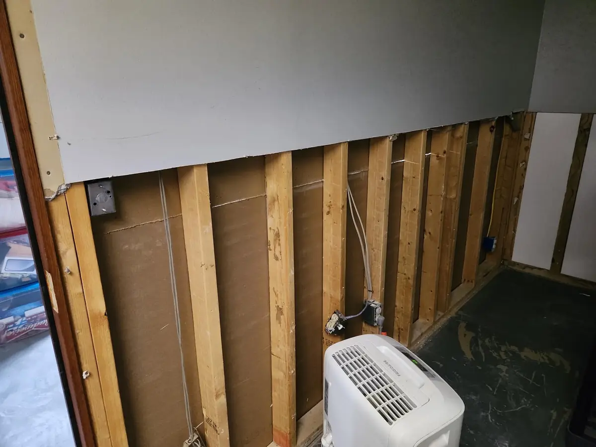 Basement walls opened up after a flood, with a dehumidifier running