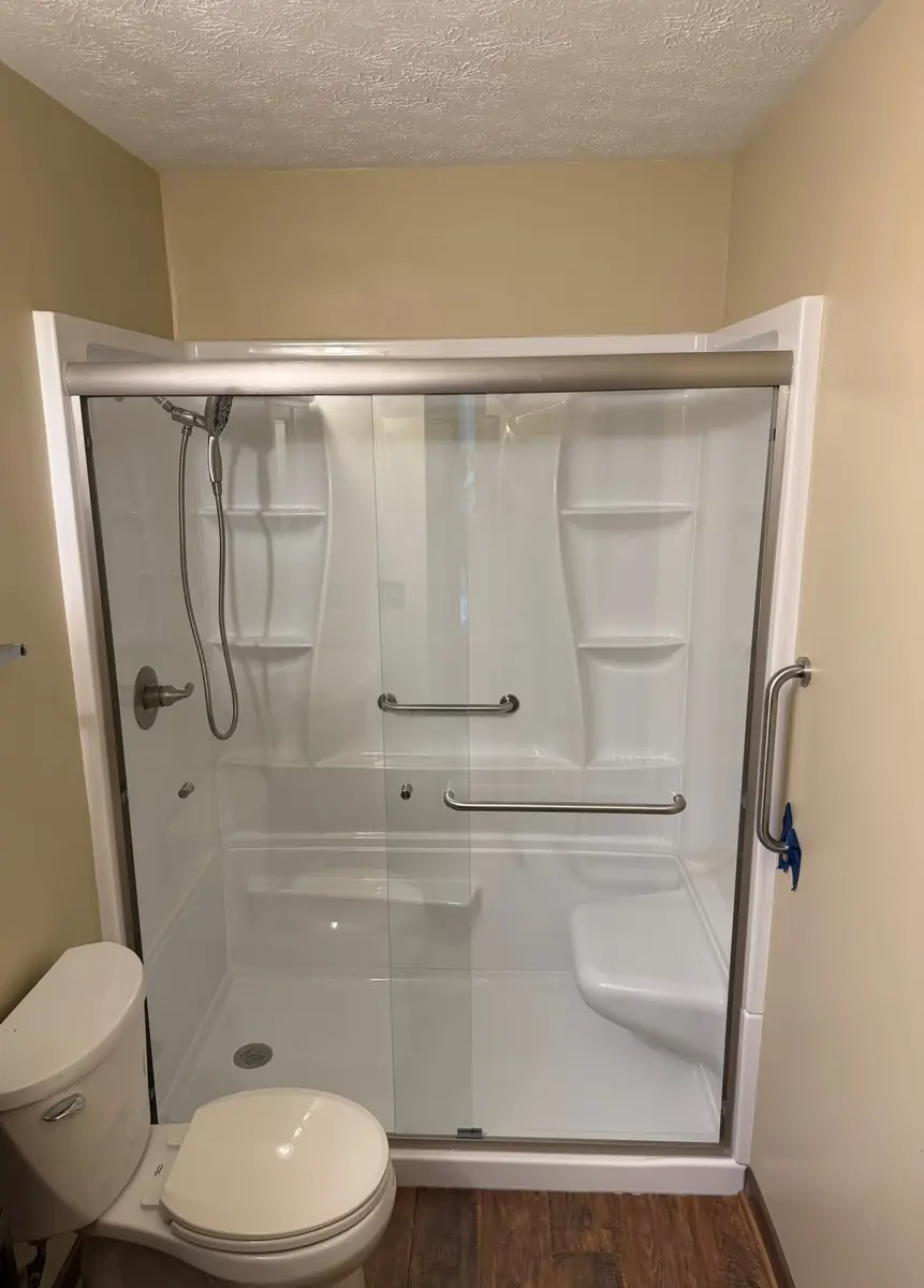 Same tub after: a new surround with a sliding glass door and grab bar