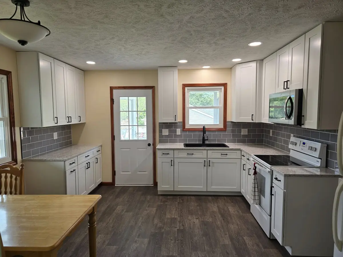 Same kitchen finished: white shaker cabinets, new countertops, backsplash and vinyl plank flooring
