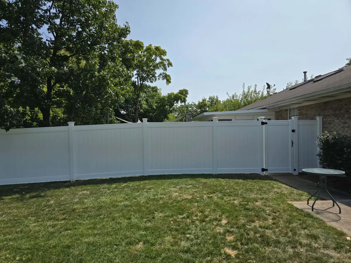 A new white vinyl privacy fence along a back yard