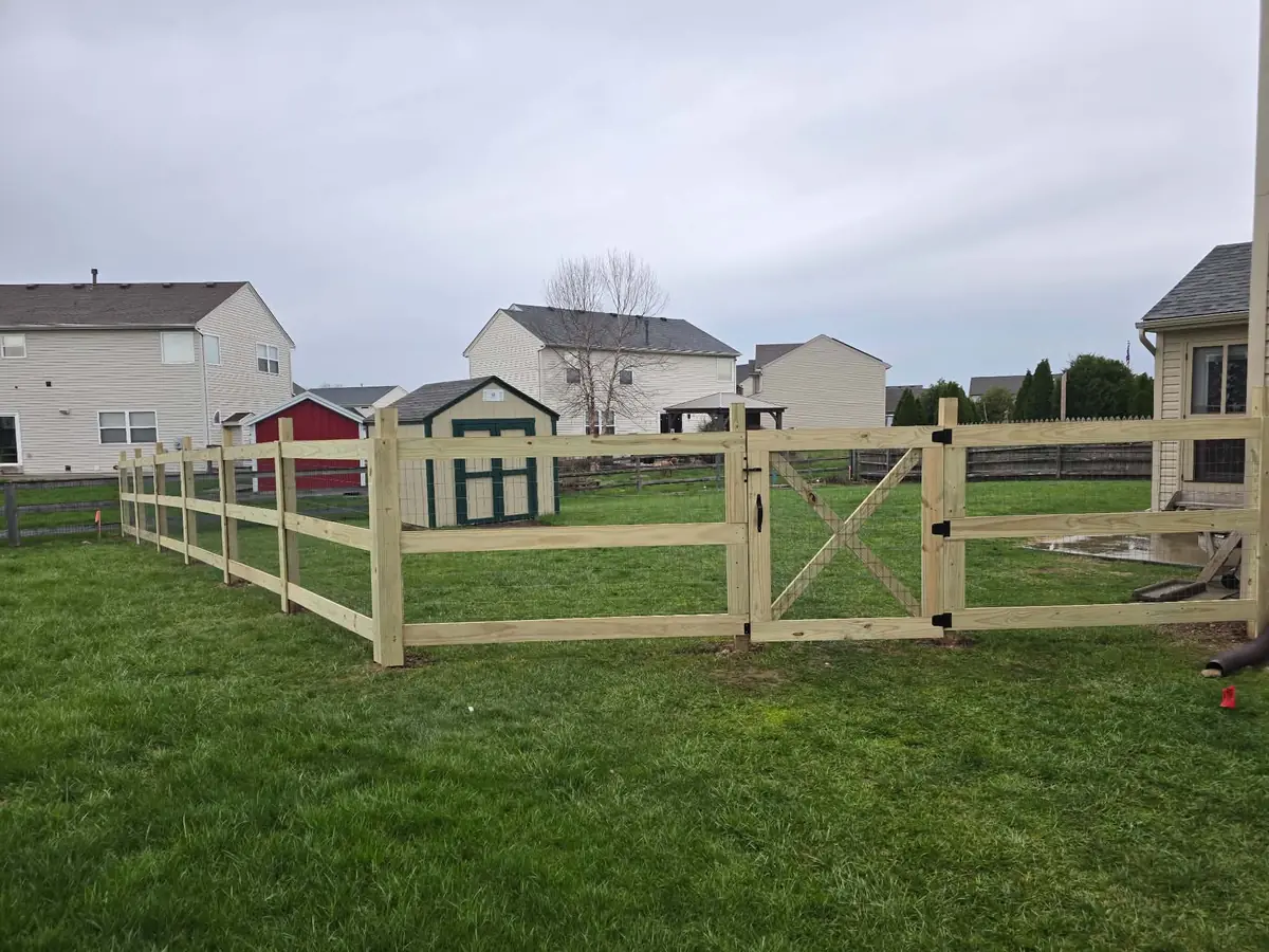 A new wood fence with a gate along a back yard, a shed behind it
